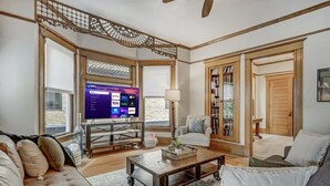 A living room with a TV, sofa, coffee table, and bookshelf.