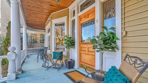A covered porch with rocking chairs and a wooden door. - Crescent Estate! Hot Tub, Mtn Views, Walk DT, Golf (Colorado Springs)