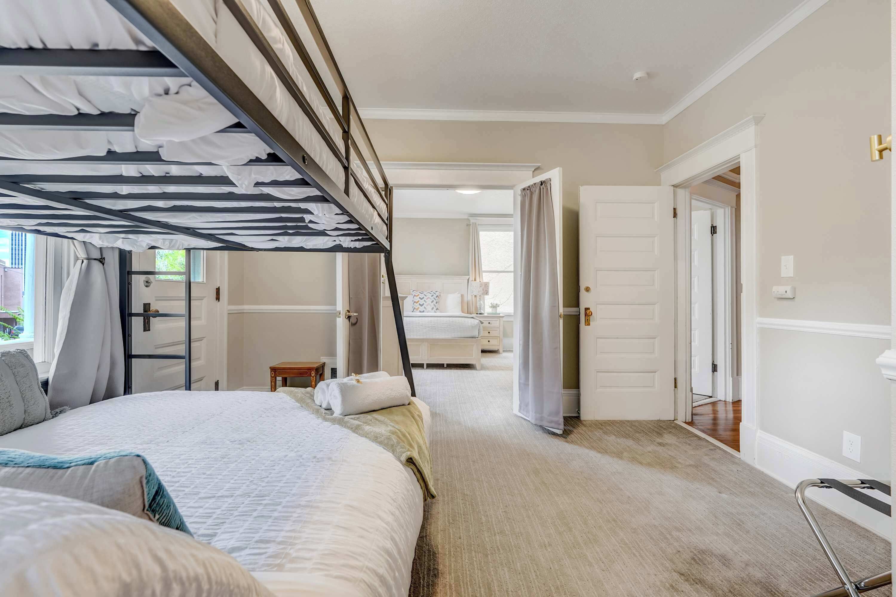 Une chambre avec un lit superposé, une table de chevet, une chaise et une vue sur le couloir.