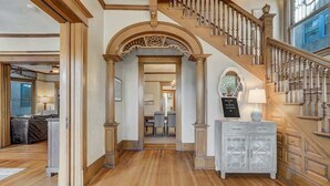 A grand staircase with ornate railings and a white console table with a sign. - Crescent Estate! Hot Tub, Mtn Views, Walk DT, Golf (Colorado Springs)