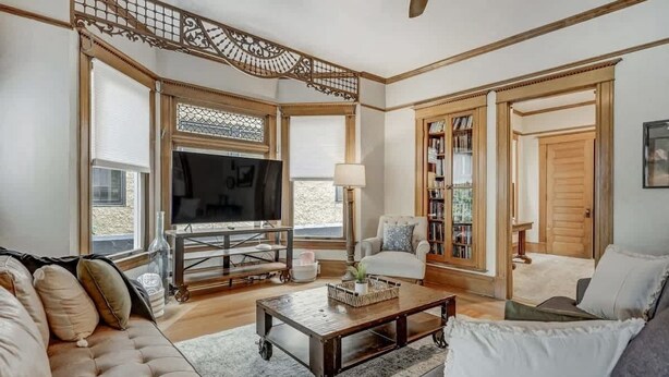A living room with a sofa, coffee table, TV, and bookshelf. - Crescent Estate! Hot Tub, Mtn Views, Walk DT, Golf (Colorado Springs)