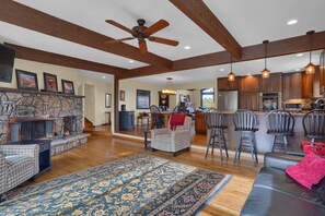 A spacious living area with a fireplace, a large rug, and a dining area with bar stools. - Scenic Mountain Views/Corporate Rental/30 day minimum (Colorado Springs)