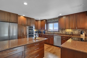 A modern kitchen with wooden cabinets, stainless steel appliances, granite countertops, and a view through a window. - Scenic Mountain Views/Corporate Rental/30 day minimum (Colorado Springs)
