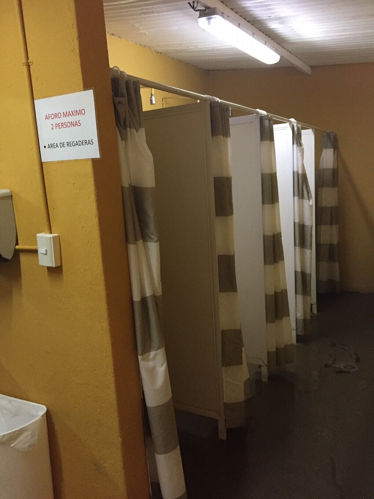 A row of curtained partitioned areas with a sign indicating a maximum of 2 people and a rest area.
