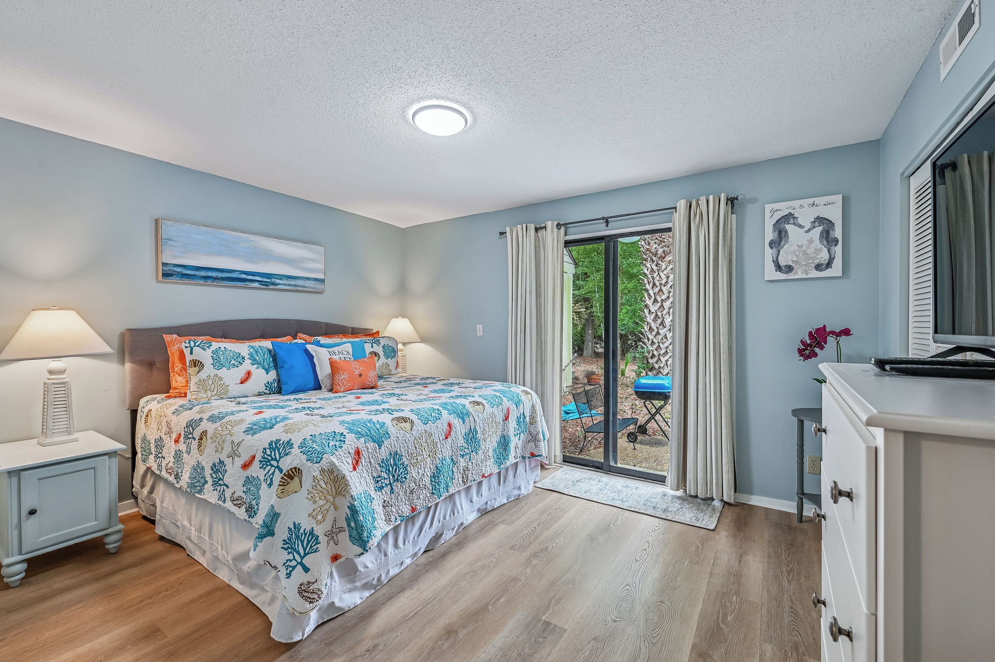 Een slaapkamer met een bed, nachtkastjes, een dressoir en uitzicht op de omgeving.