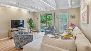 A spacious living room with a large TV, comfortable seating, and a view of the outdoors.