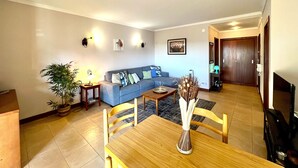 Un salon avec un canapé, une table à manger et des chaises, une plante en pot et un vase.