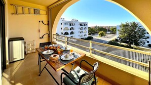 Un balcon avec une table dressée pour le petit-déjeuner, une vue sur les bâtiments et une rambarde jaune.