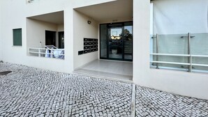 Un bâtiment moderne doté d’un hall d’entrée carrelé, d’une porte en verre et d’une rambarde en métal.