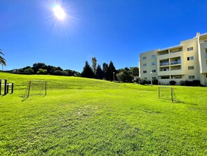 A grassy field with two soccer goals and a building in the background.