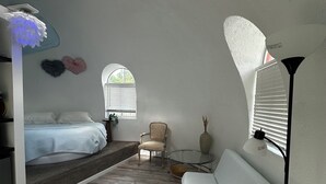 Een kamer met een bed, een stoel, een bank, een klein tafeltje en een lamp.