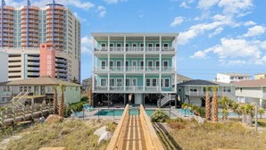 Ein mehrstöckiges Hotel mit Pool und einer Holzterrasse im Vordergrund.