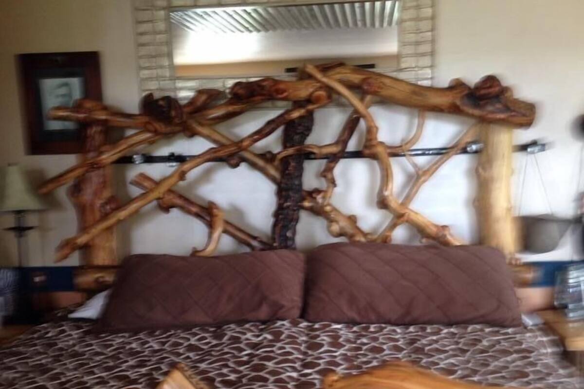 A bed with a unique wooden headboard and patterned bedding.