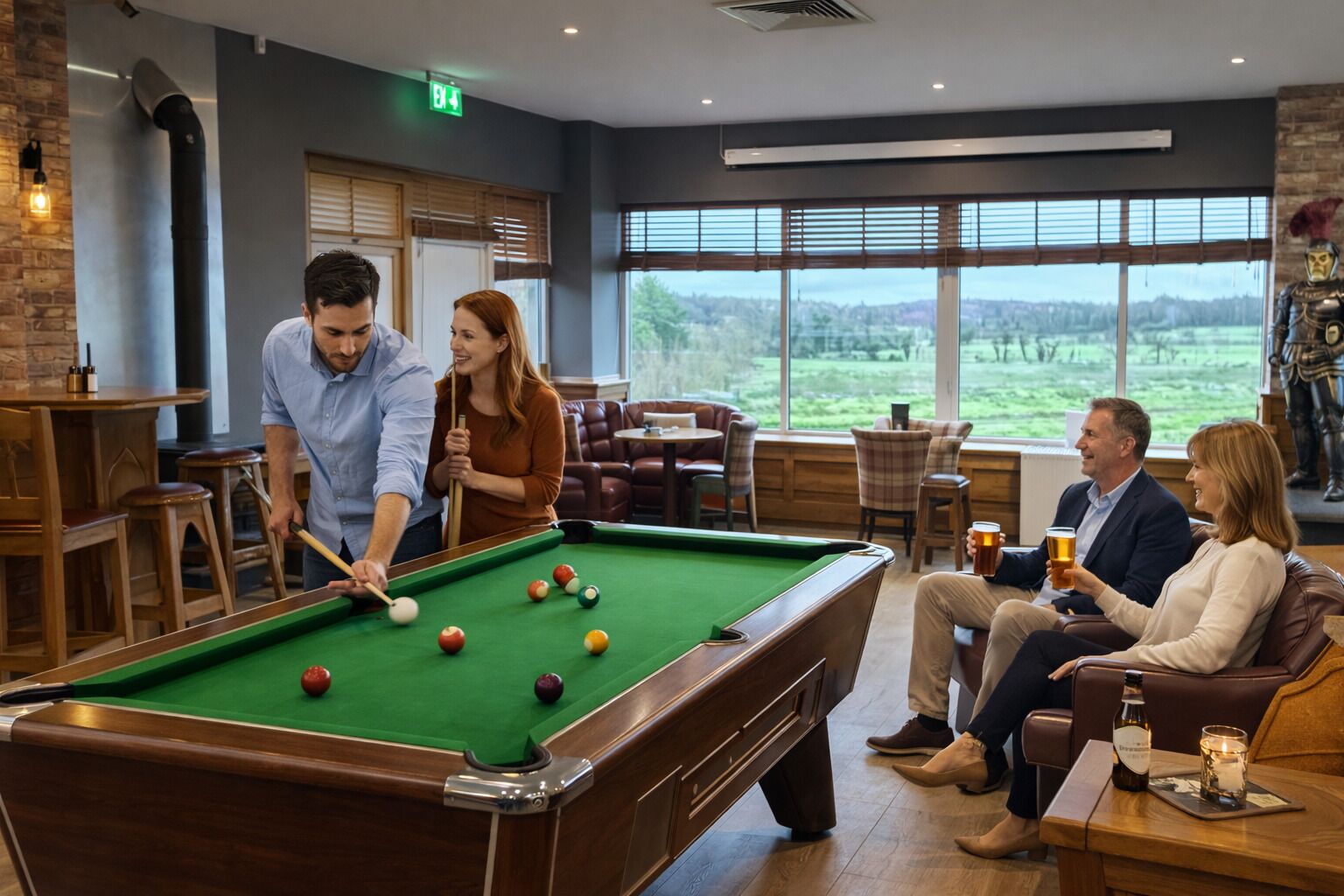 A pool table in a room with large windows, a fireplace, and a statue.