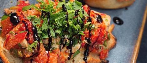 Two open-faced sandwiches with toppings and a drizzle of sauce on a rectangular plate.