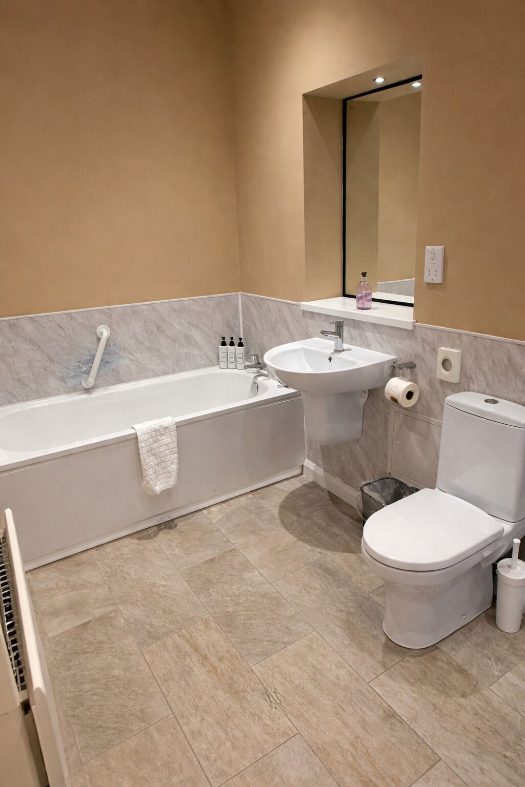 Un baño moderno con bañera, lavabo, inodoro y espejo.