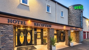 Eine Hotelrezeption mit einer Stein-Fassade, ein Restaurant und ein Schild mit der Aufschrift 'The Hedge'.