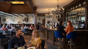 Ein Restaurant mit Holzbalken, Kronleuchtern und einer Bar.