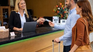 Ein Empfangstresen mit einem Laptop, einem WLAN-Symbol und einer Blumenkomposition.