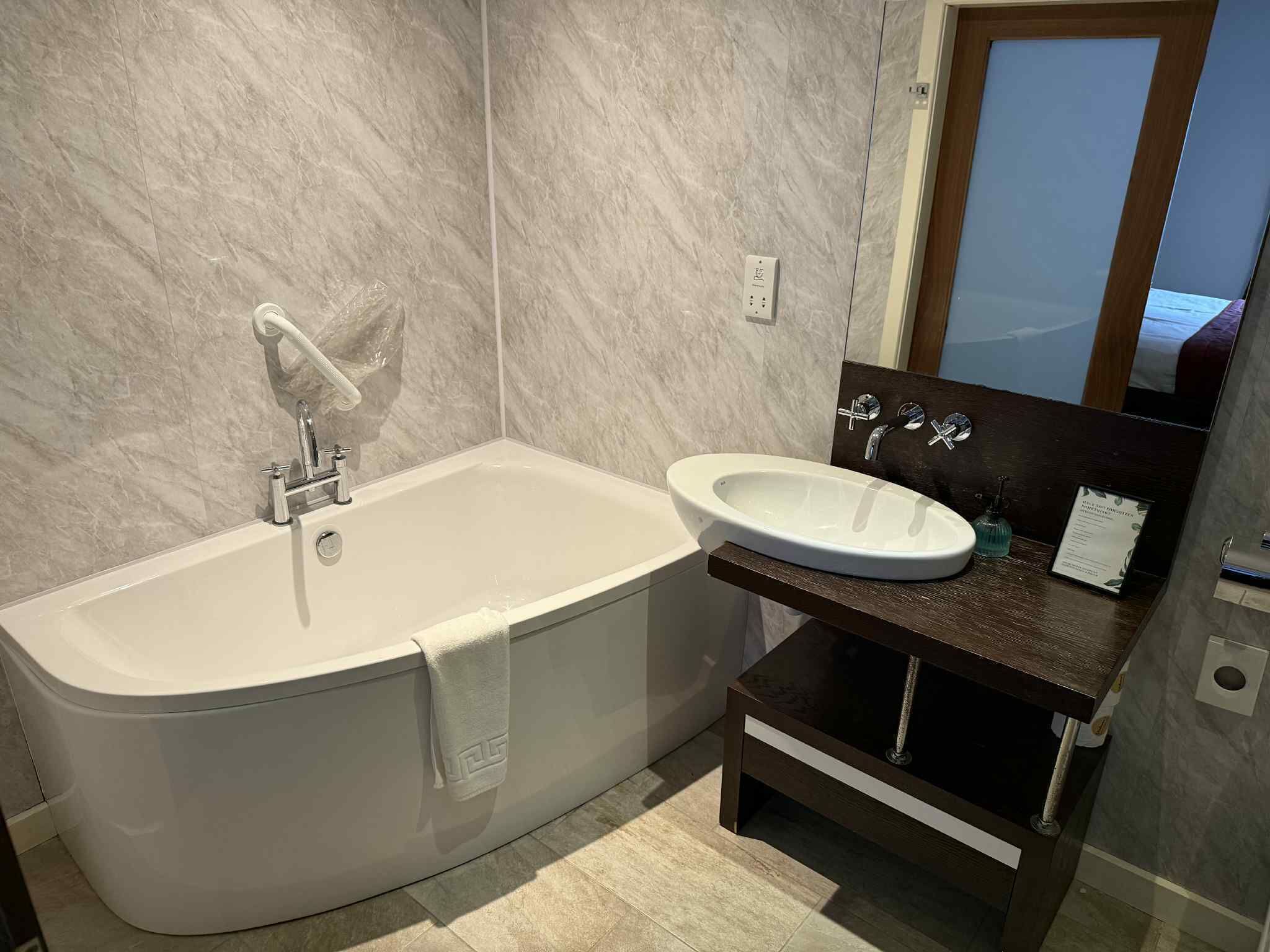 A bathroom with a bathtub, a sink, and a mirror.