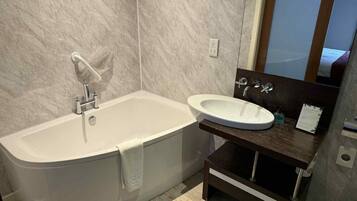 A bathroom with a bathtub, a sink, and a mirror.