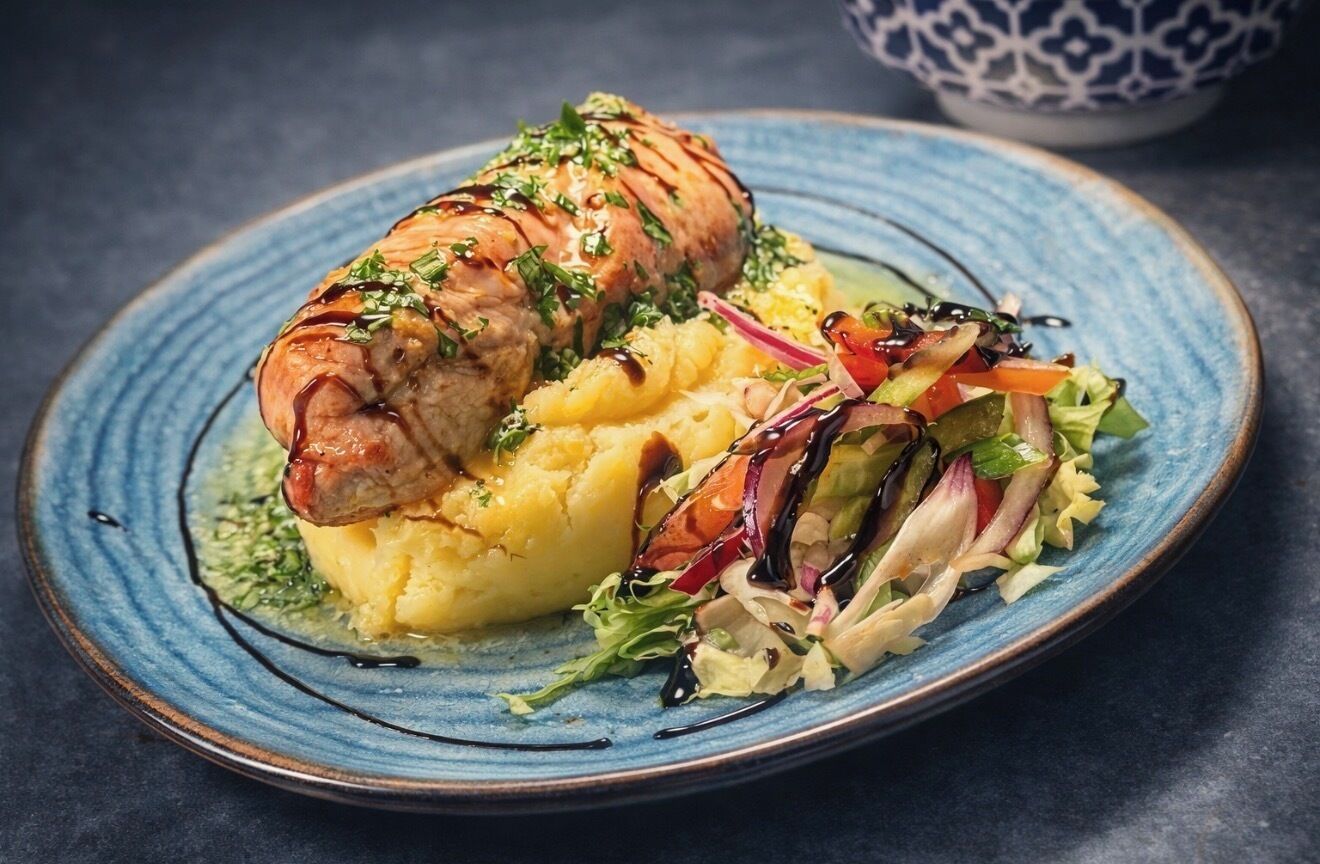 En tallrik med tillagat kött, potatismos och en sallad som tillbehör.