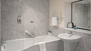Un baño moderno con una bañera independiente, un lavamanos montado en la pared y un espejo grande.