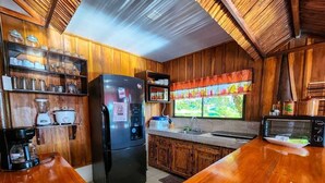 Eine Küche mit Holzschränken, einem Kühlschrank, einer Mikrowelle und einer Kaffeemaschine.