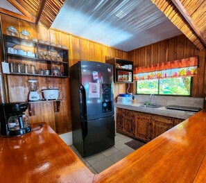 Una cocina con armarios de madera, un refrigerador, un microondas y una cafetera.