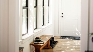 A hallway with a wooden bench, a white door, and windows with black frames. - The Lucky Penny Farmhouse on the LBJ Grasslands (Alvord)