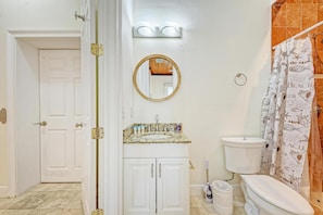 Ein Badezimmer mit Toilette, einem Waschbecken mit Marmorplatte, einem Spiegel über dem Waschbecken und einer Duschvorhang mit Strandmotiv.