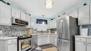 Una cucina moderna con elettrodomestici in acciaio inossidabile, mobili bianchi e uno schienale blu e bianco.