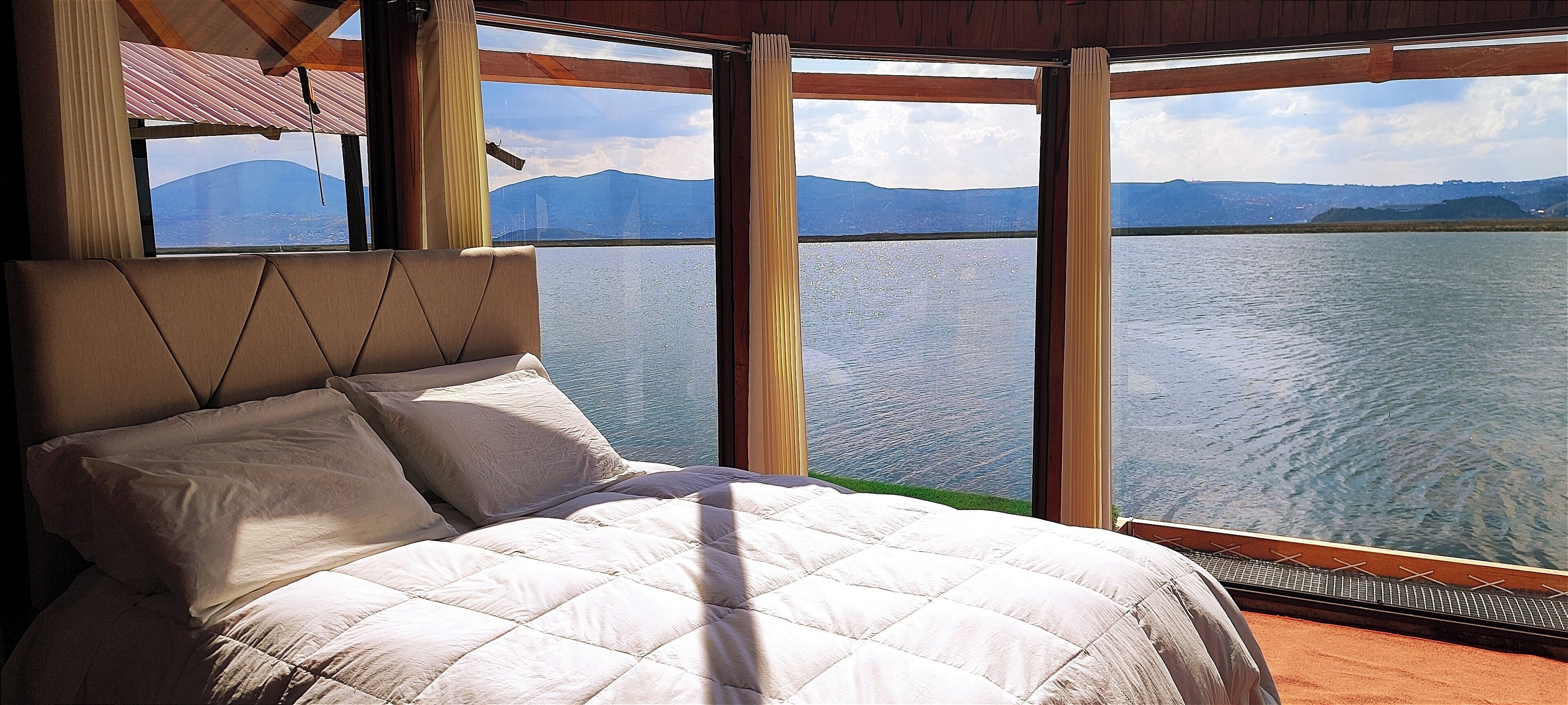 Una cama con vistas a un lago y montañas.