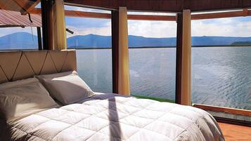 Una cama con vistas a un lago y montañas.