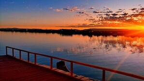 A wooden pier extending into calm water with a sunset in the background. - Vanalux Titicaca (Puno)