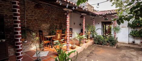 A courtyard with brick columns, potted plants, and a tiled floor.