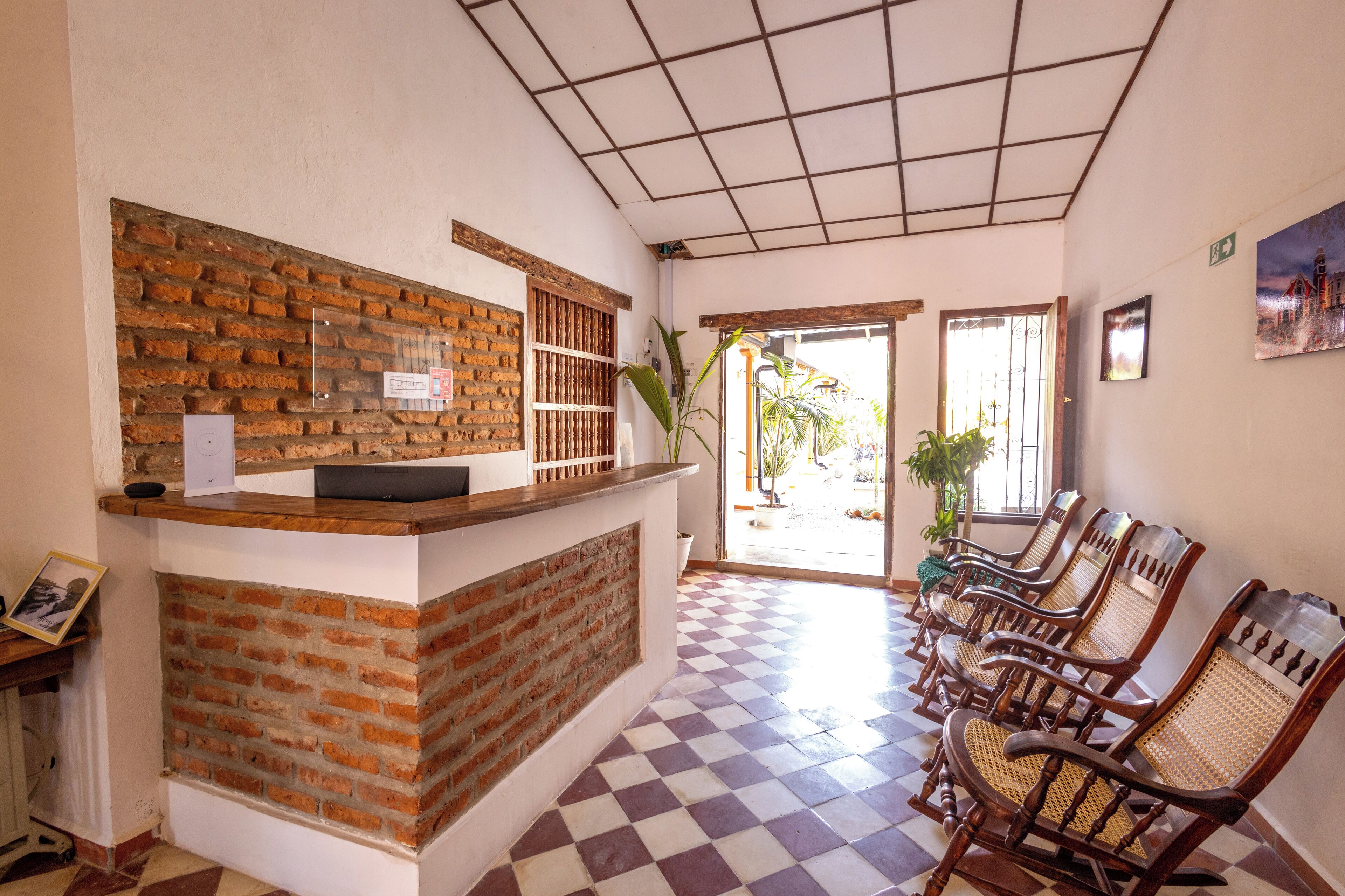 A reception area with a brick counter, check-in desk, and a row of wooden chairs.