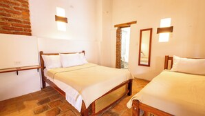 Una habitación con dos camas de madera, una pared de ladrillo y una puerta de madera.