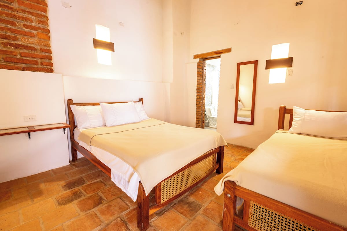 A room with two wooden beds, a brick wall, and a wooden door.