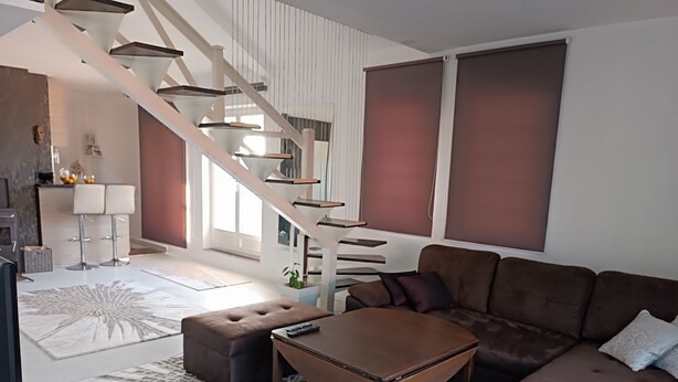 A modern living room with a brown leather sofa, a coffee table, and a staircase leading to an upper level. - Modern duplex with amazing view (Beograd)