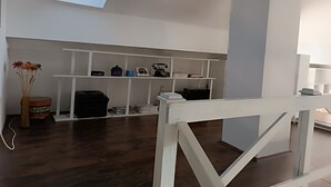 A modern room with a skylight, white shelving with various items, a wooden floor, and a white bench. - Modern duplex with amazing view (Beograd)