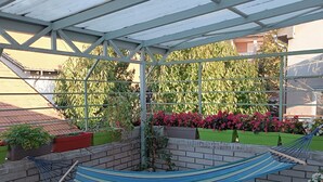 A covered patio with a hammock, seating area, and potted plants. - Modern duplex with amazing view (Beograd)