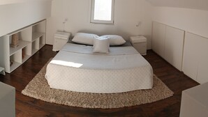 A bedroom with a bed, two bedside tables, a window, and built-in shelving. - Modern duplex with amazing view (Beograd)