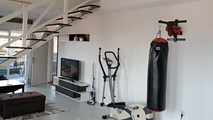 A spacious living area with a staircase, exercise equipment, and a punching bag. - Modern duplex with amazing view (Beograd)