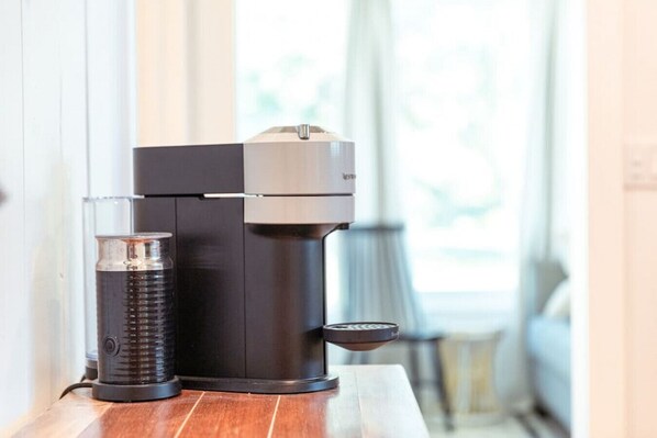 A compact, modern coffee machine with a water reservoir and a drip tray on a wooden surface. - Waterfront Bungalow, Indy River House (Fort Pierce)