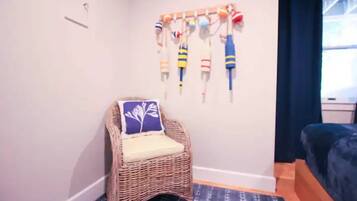 A room with a wicker chair, a wall-mounted ball rack, and a bed.