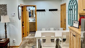 A dining area with a white table and chairs, a wooden cabinet with a 'Wi-Fi' sign, and a tiled floor. - Recently Renovated Ski In-Out on Purgatory Mountain (Durango)