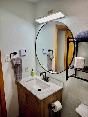 Een bad/douchecombinatie, handdoeken, toiletpapier