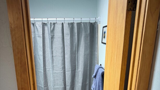 A bathroom with a toilet, a shower curtain, a towel rack, and a blue rug. - Recently Renovated Ski In-Out on Purgatory Mountain (Durango)