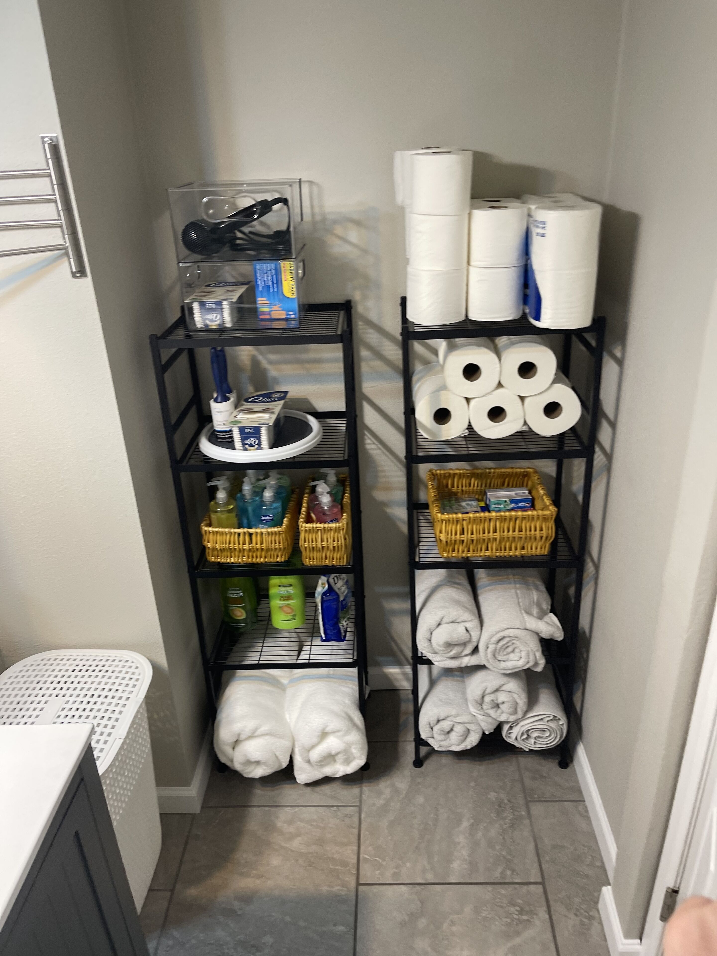 A small laundry room with shelves holding towels, toiletries, and cleaning supplies.